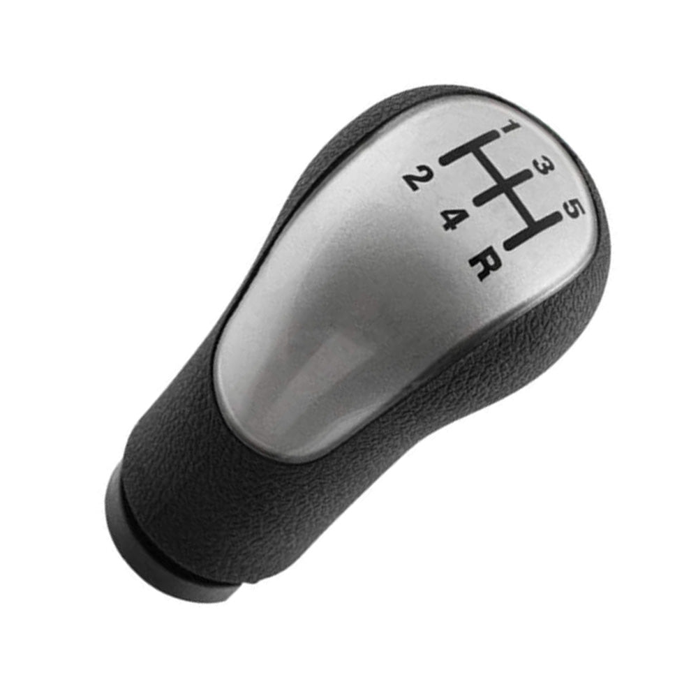 Fekete színű, 5 sebességes Ford váltógomb. Ezüst színű üveg számlappal.